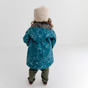 Girls rain jacket. Girl faces away from the camera wearing blue raincoat.
