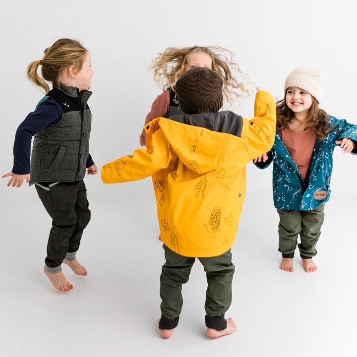Four kids wearing Wild Island clothing jump and play together. Kids waterproof raincoat is centred.