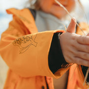 Sleeve of childrens raincoat in mustard yellow features ribbed cuffs and mid weight cotton jersey lining